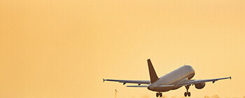 Commercial aircraft climbing into a golden sky, illustrating fuel savings, lower emissions, and smoother operations from continuous climb and descent procedures.