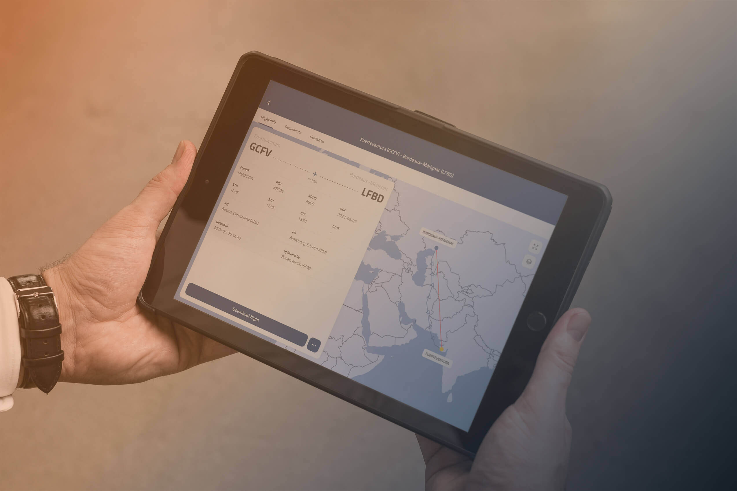 Person holding a tablet displaying a flight route from GCFV to LFBD with operational data for paperless cockpit use.