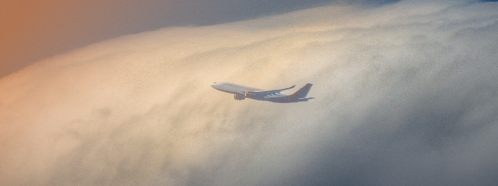 A modern airplane flying above the clouds, symbolizing how technology in flight planning enhances operational flexibility and efficiency.