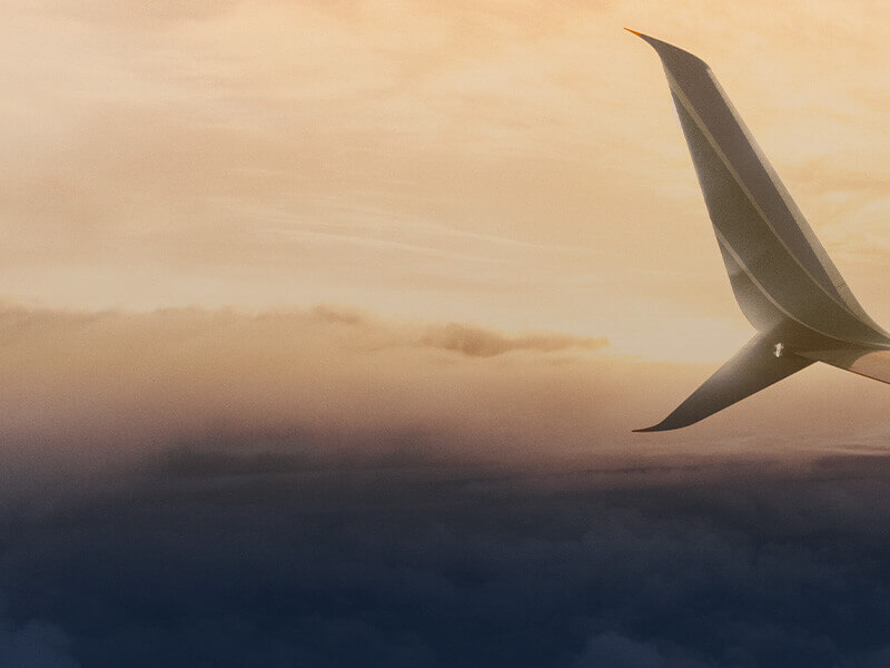 Close-up of an aircraft wingtip against a warm sunset sky above cloud layers, representing smooth cruise flight, efficiency, and stable flight operations.