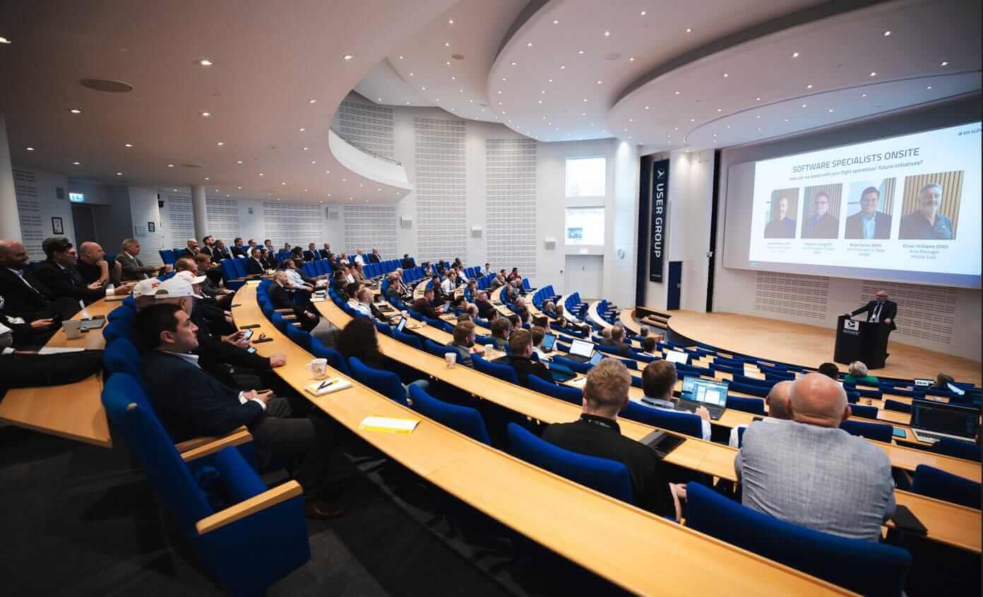 Photo from UGM 2024 showing the presentation of some of the software specialists who are onsite at this year's event. More than 150 people are listening to the host speaking from the stage.